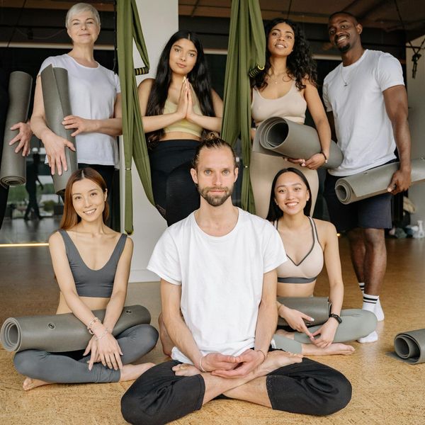 Group of diverse people sitting on yoga mats smiling.